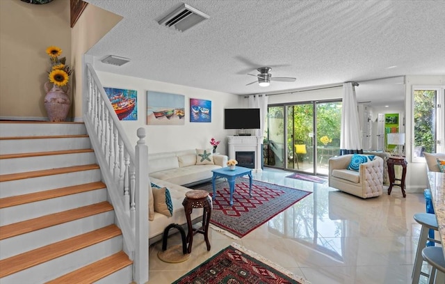 2934 Oceans Trce, Daytona Beach Shores, FL 32118 - tiled living room with plenty of natural light, a textured ceiling, a ceiling fan, stairway, and a fireplace