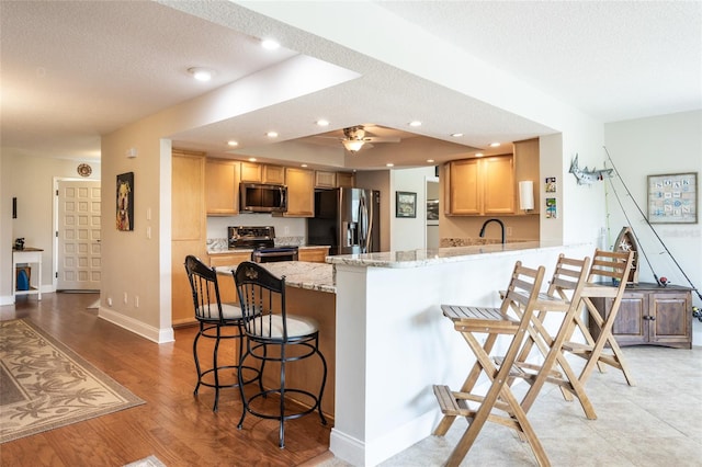 40 Cloverdale Ct N, Palm Coast, FL 32137 - kitchen featuring appliances with stainless steel finishes, a peninsula, a kitchen bar, light wood-style flooring, and a textured ceiling