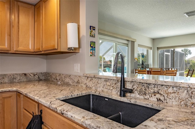 40 Cloverdale Ct N, Palm Coast, FL 32137 - kitchen featuring a sink, a textured ceiling, and light stone counters