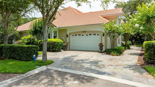 129 Front St, Palm Coast, FL 32137 - view of front of house with a tiled roof, driveway, a garage, and stucco siding