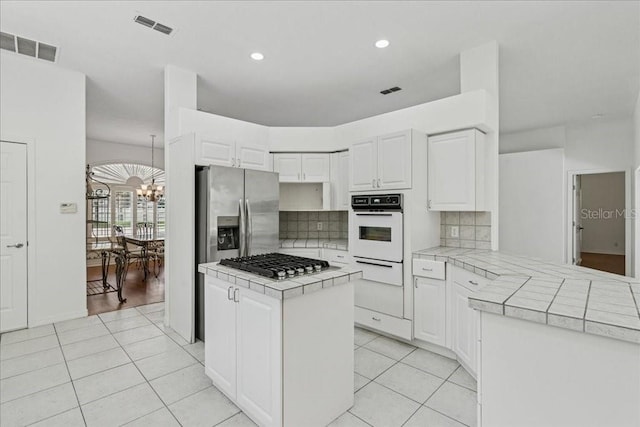 49 Ludlow Ln W, Palm Coast, FL 32137 - kitchen with appliances with stainless steel finishes, tile countertops, a warming drawer, a chandelier, and recessed lighting
