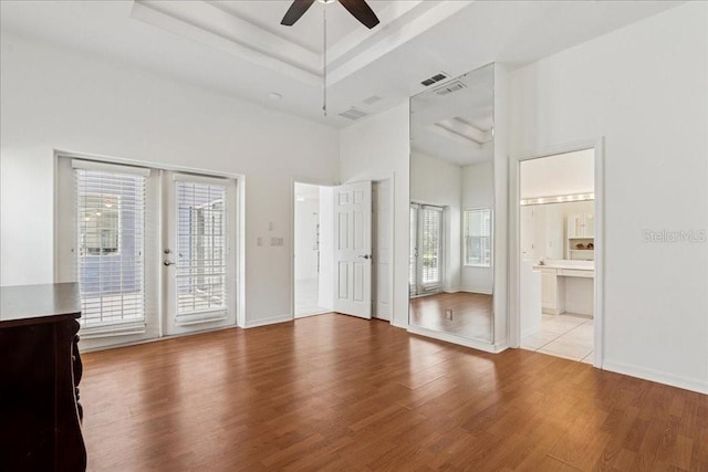 49 Ludlow Ln W, Palm Coast, FL 32137 - unfurnished bedroom featuring access to outside, wood finished floors, multiple windows, a tray ceiling, and a towering ceiling