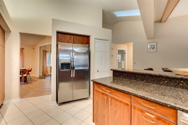 29 Cherrytree Ct, Palm Coast, FL 32137 - kitchen featuring stainless steel fridge with ice dispenser, light tile patterned floors, a skylight, dark stone counters, and brown cabinets