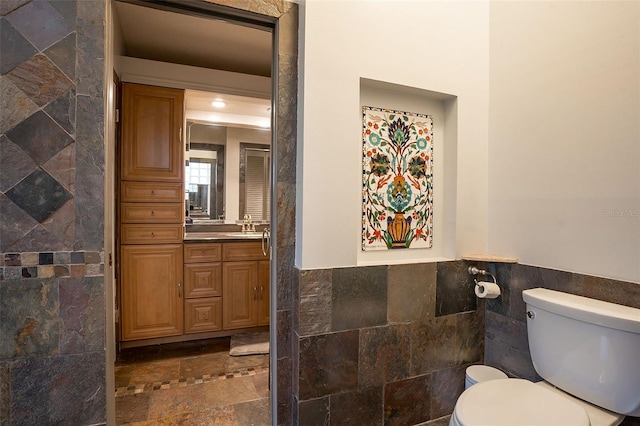 29 Cherrytree Ct, Palm Coast, FL 32137 - bathroom featuring tile walls, stone tile flooring, vanity, toilet, and wainscoting