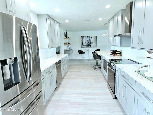 13 Sunrise Ave, Ormond Beach, FL 32176 - kitchen featuring appliances with stainless steel finishes, wall chimney exhaust hood, light stone counters, recessed lighting, and light wood finished floors
