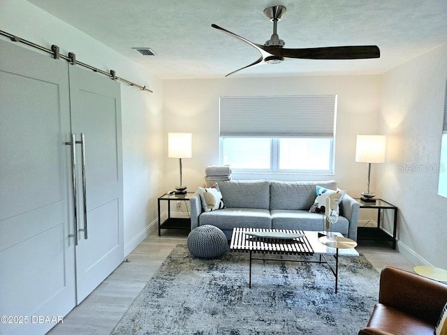 13 Sunrise Ave, Ormond Beach, FL 32176 - living room with a ceiling fan, a barn door, light wood-style flooring, and baseboards