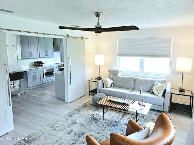 13 Sunrise Ave, Ormond Beach, FL 32176 - living area featuring light wood-style floors, a barn door, ceiling fan, and baseboards