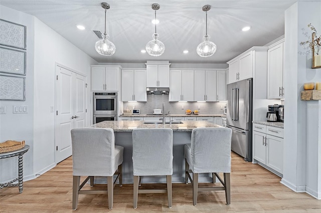 100 Las Casitas Blvd, Palm Coast, FL 32137 - kitchen with stainless steel appliances, white cabinetry, a kitchen bar, and recessed lighting