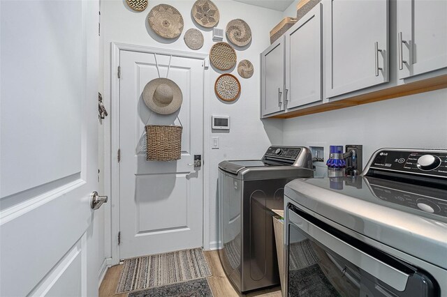 100 Las Casitas Blvd, Palm Coast, FL 32137 - laundry room featuring washing machine and clothes dryer, light wood finished floors, and cabinet space