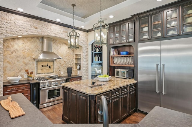 140 Monterey Bay Ln, Green Cove Springs, FL 32043 - kitchen with high quality appliances, wall chimney range hood, dark wood-style flooring, light stone countertops, and dark brown cabinets