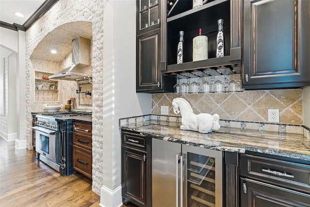 140 Monterey Bay Ln, Green Cove Springs, FL 32043 - indoor dry bar with wall chimney range hood, high end stainless steel range, arched walkways, decorative backsplash, and light wood finished floors