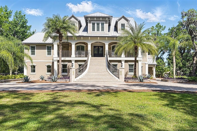 140 Monterey Bay Ln, Green Cove Springs, FL 32043 - coastal home featuring stairs, stucco siding, covered porch, metal roof, and a front lawn