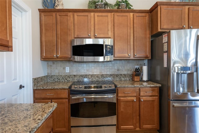 200 Bella Harbor Ct Unit 113, Palm Coast, FL 32137 - kitchen with stainless steel appliances, brown cabinets, backsplash, and light stone counters