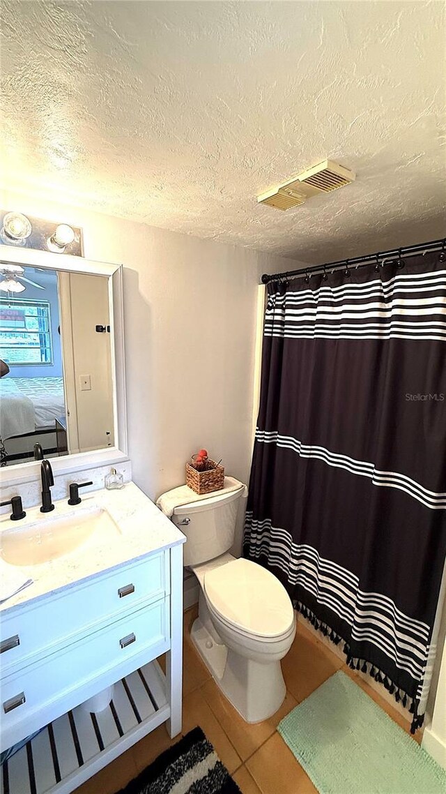 1640 Juno Trl Unit 202E, Astor, FL 32102 - ensuite bathroom featuring toilet, vanity, a textured ceiling, tile patterned flooring, and curtained shower