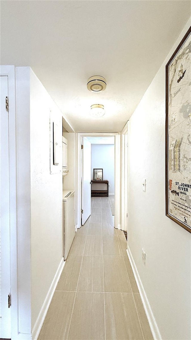 1640 Juno Trl Unit 202E, Astor, FL 32102 - hallway featuring estacked washer and dryer, baseboards, and light tile patterned floors