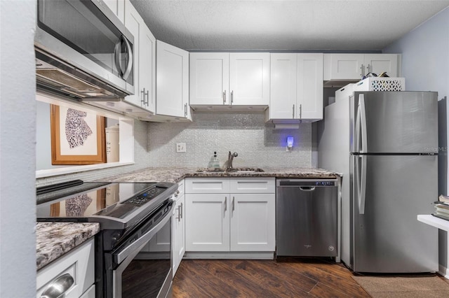 640 N Nova Rd Unit 117, Ormond Beach, FL 32174 - kitchen featuring appliances with stainless steel finishes, a sink, light stone counters, white cabinetry, and decorative backsplash
