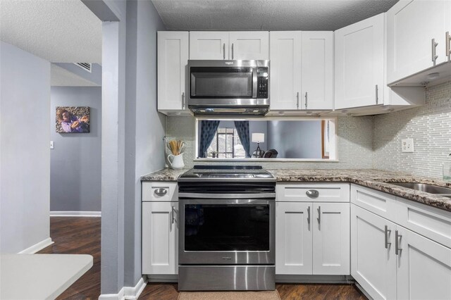 640 N Nova Rd Unit 117, Ormond Beach, FL 32174 - kitchen with stainless steel appliances, decorative backsplash, white cabinets, dark wood-style floors, and a textured ceiling