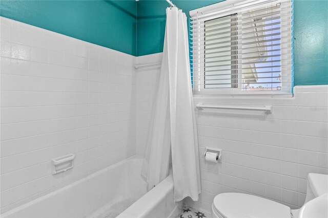 129 Dundee Rd, Daytona Beach, FL 32118 - full bath featuring tile walls, shower / tub combo, toilet, and wainscoting
