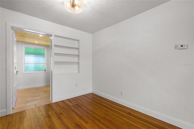129 Dundee Rd, Daytona Beach, FL 32118 - spare room featuring built in shelves, baseboards, and wood finished floors