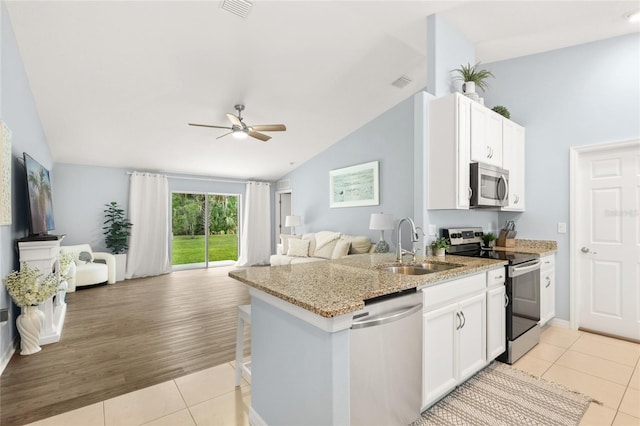 217 Birchwood Dr, Palm Coast, FL 32137 - kitchen featuring appliances with stainless steel finishes, open floor plan, a sink, lofted ceiling, and light tile patterned floors