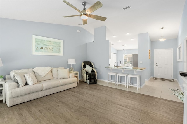 217 Birchwood Dr, Palm Coast, FL 32137 - living area featuring ceiling fan, light wood-style floors, vaulted ceiling, and baseboards