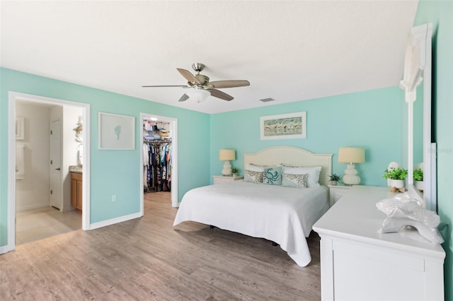 217 Birchwood Dr, Palm Coast, FL 32137 - bedroom with a walk in closet, light wood-style floors, a closet, baseboards, and ceiling fan
