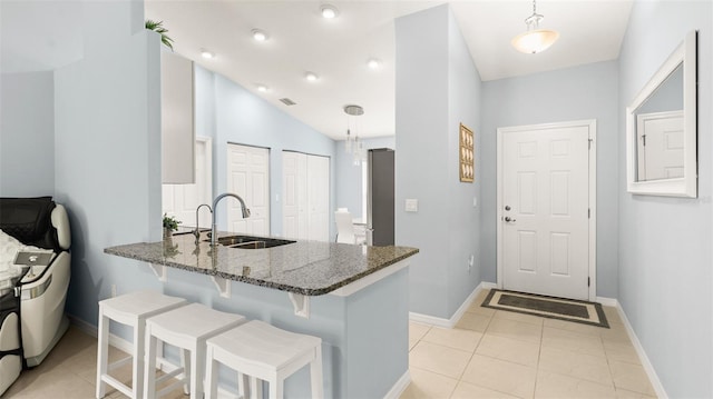 217 Birchwood Dr, Palm Coast, FL 32137 - kitchen with a sink, dark stone countertops, a peninsula, a breakfast bar, and baseboards