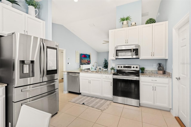 217 Birchwood Dr, Palm Coast, FL 32137 - kitchen featuring stainless steel appliances, vaulted ceiling, a sink, a peninsula, and white cabinetry