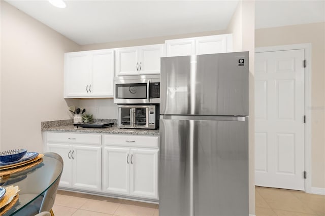 217 Birchwood Dr, Palm Coast, FL 32137 - kitchen featuring stainless steel appliances, light tile patterned floors, light stone counters, and white cabinets