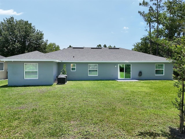 217 Birchwood Dr, Palm Coast, FL 32137 - back of property featuring cooling unit, a yard, stucco siding, and roof with shingles