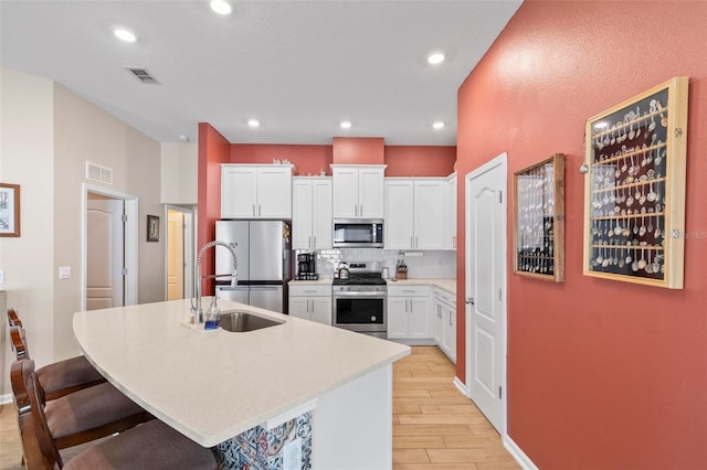 65 Lob Wedge Ln, Bunnell, FL 32110 - kitchen featuring appliances with stainless steel finishes, a sink, light wood-type flooring, backsplash, and an island with sink