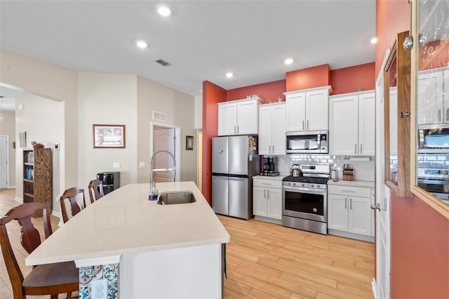 65 Lob Wedge Ln, Bunnell, FL 32110 - kitchen featuring appliances with stainless steel finishes, a sink, a breakfast bar, tasteful backsplash, and light wood-style floors