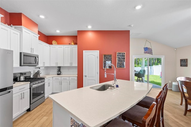 65 Lob Wedge Ln, Bunnell, FL 32110 - kitchen with stainless steel appliances, a sink, light wood-type flooring, a kitchen bar, and white cabinets