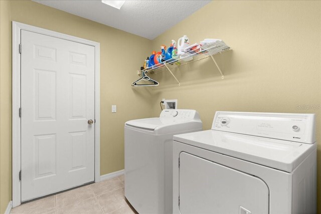 58 Slocum Path, Palm Coast, FL 32164 - laundry area with washing machine and dryer, baseboards, light tile patterned floors, and a textured ceiling