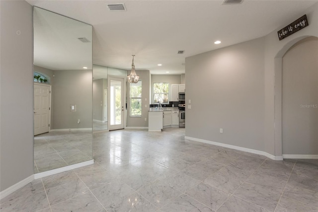 45 Atlantic Dr, Palm Coast, FL 32137 - unfurnished living room featuring baseboards, recessed lighting, a chandelier, and arched walkways