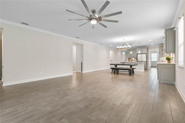 13 Las Brisas Way, Palm Coast, FL 32137 - unfurnished living room featuring a ceiling fan, light wood-style flooring, ornamental molding, a chandelier, and baseboards