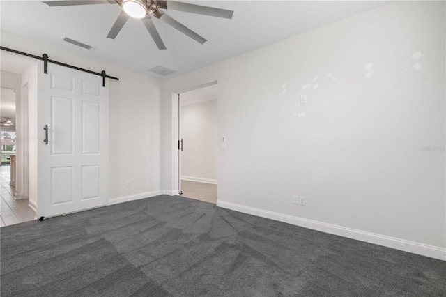 13 Las Brisas Way, Palm Coast, FL 32137 - unfurnished bedroom with a barn door, dark carpet, baseboards, and a ceiling fan