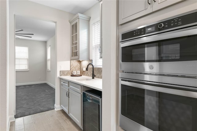 13 Las Brisas Way, Palm Coast, FL 32137 - kitchen with a sink, stainless steel double oven, light countertops, backsplash, and glass insert cabinets