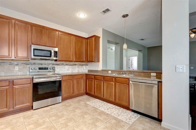 1 Rockwell Ln W, Palm Coast, FL 32164 - kitchen featuring stainless steel appliances, a sink, backsplash, brown cabinetry, and a textured ceiling