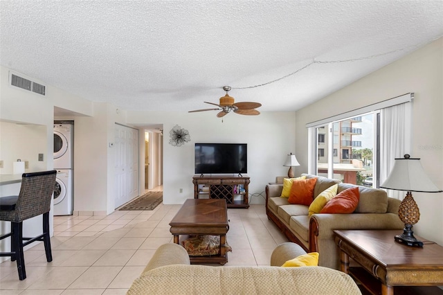 3600 S Ocean Shore Blvd Unit 222, Flagler Beach, FL 32136 - living room featuring stacked washer and clothes dryer, a textured ceiling, a ceiling fan, and light tile patterned flooring