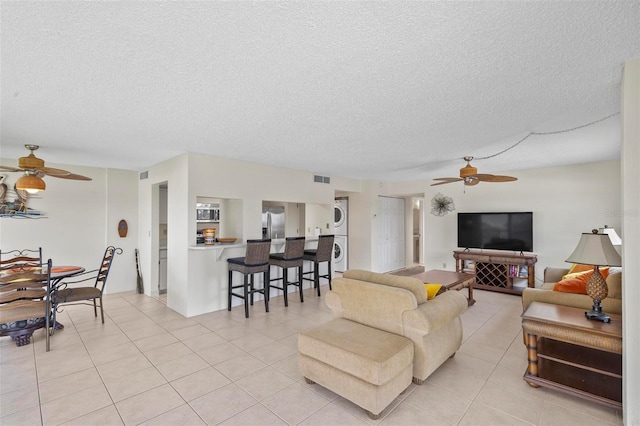 3600 S Ocean Shore Blvd Unit 222, Flagler Beach, FL 32136 - living area featuring stacked washer and clothes dryer, ceiling fan, a textured ceiling, and light tile patterned floors