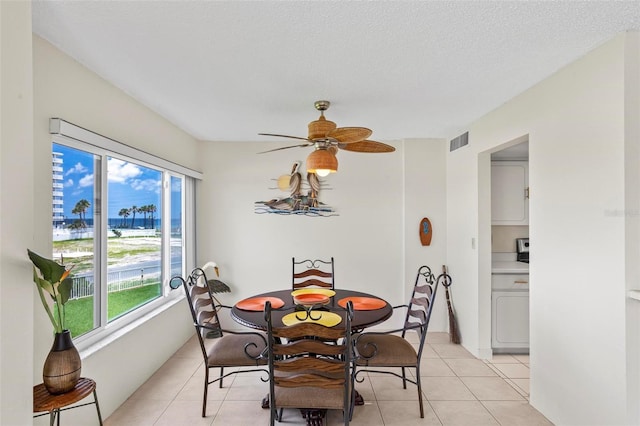 3600 S Ocean Shore Blvd Unit 222, Flagler Beach, FL 32136 - dining room with a water view, light tile patterned floors, ceiling fan, and a textured ceiling