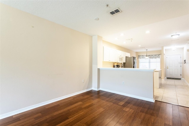 1100 Canopy Walk Ln Unit 1113, Palm Coast, FL 32137 - kitchen featuring stainless steel fridge, hardwood / wood-style flooring, white microwave, white cabinets, and a peninsula