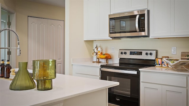 115 Wellwood Ln Unit A, Palm Coast, FL 32164 - kitchen featuring stainless steel microwave, range with electric cooktop, white cabinetry, and light countertops