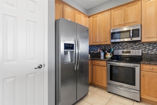 1200 Cinnamon Beach Way Unit 1133, Palm Coast, FL 32137 - kitchen featuring stainless steel appliances, light tile patterned floors, tasteful backsplash, and dark stone countertops