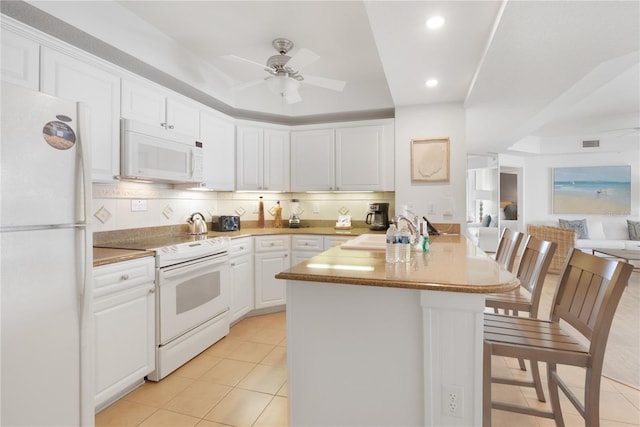 200 Ocean Crest Dr Unit 605, Palm Coast, FL 32137 - kitchen with white appliances, a ceiling fan, a peninsula, white cabinets, and a breakfast bar area