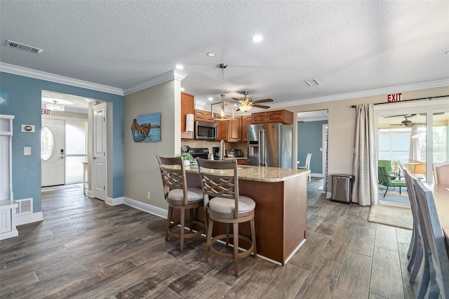 7 Fleming Ct, Palm Coast, FL 32137 - kitchen with appliances with stainless steel finishes, ceiling fan, a textured ceiling, dark wood-type flooring, and crown molding