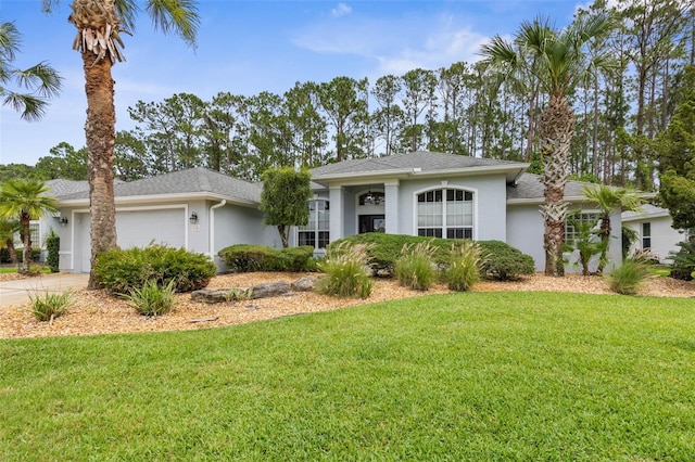 115 Bay Lake Dr, Ormond Beach, FL 32174 - view of front of home with stucco siding, an attached garage, a front lawn, and driveway