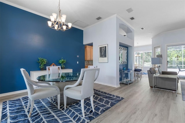 115 Bay Lake Dr, Ormond Beach, FL 32174 - dining area with a chandelier, light wood-style flooring, crown molding, and baseboards