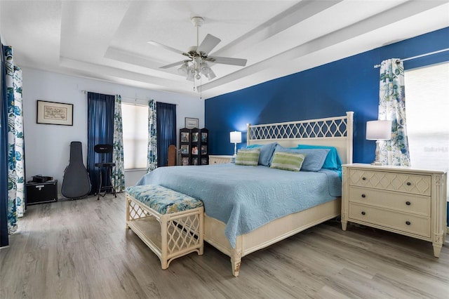115 Bay Lake Dr, Ormond Beach, FL 32174 - bedroom featuring wood finished floors, a tray ceiling, and a ceiling fan